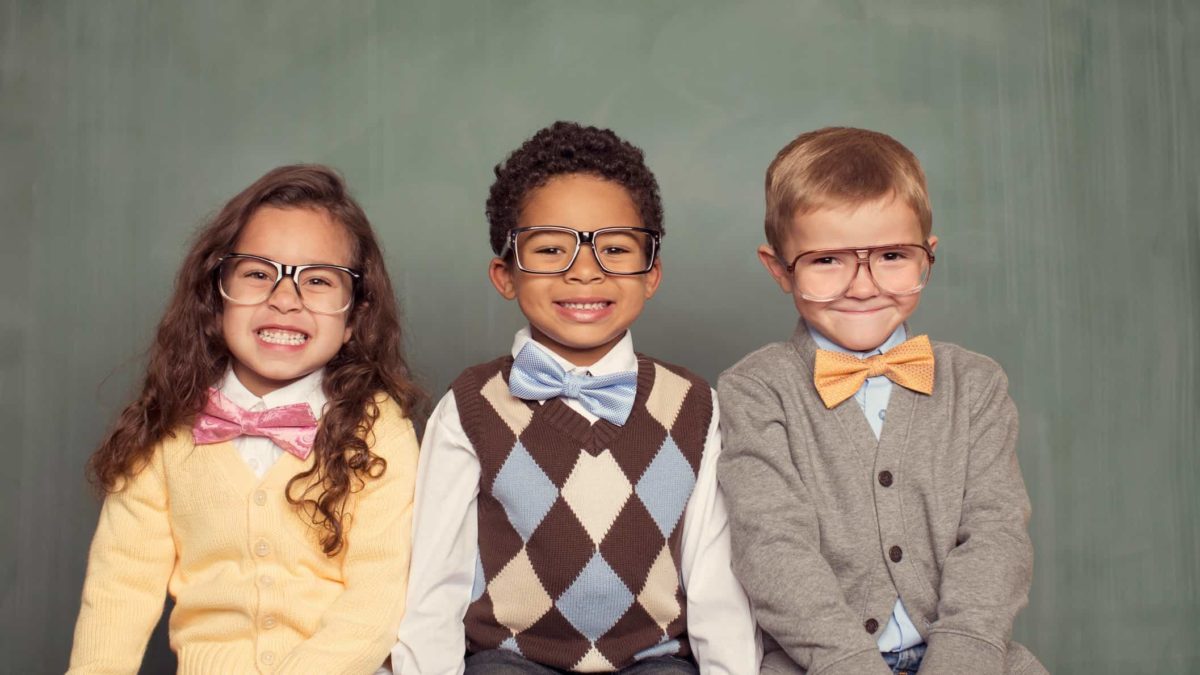 a group of smart looking kids, wearing formal clothes and all with spectacles, sit in a line and smile charmingly.