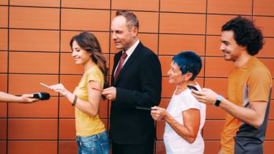 a line of buyers form a queue holding their phones to tap on a payment machine.