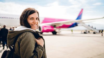 A woman smiles as she crosses the tarmac, happy to be boarding a plane at the airport and travelling again.