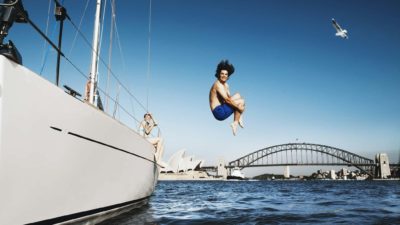 A young man leaps into the water from a sail boat in Sydney Harbour.