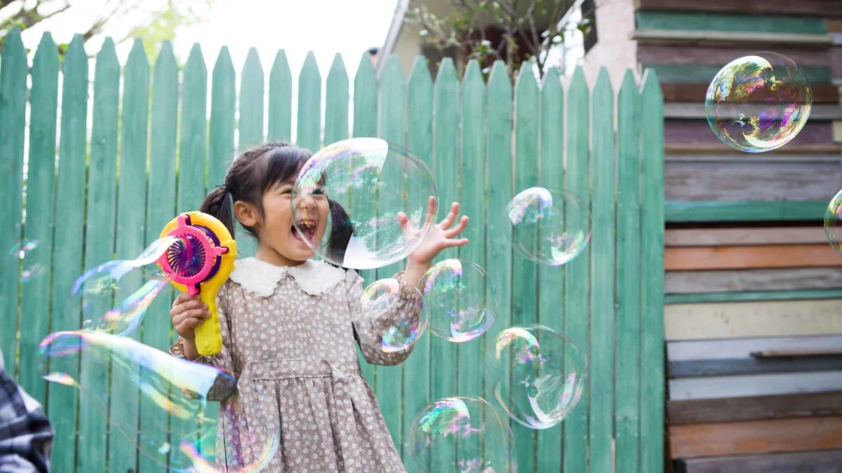 A little Asian girl is so excited by the bubbles coming out of her bubble machine.