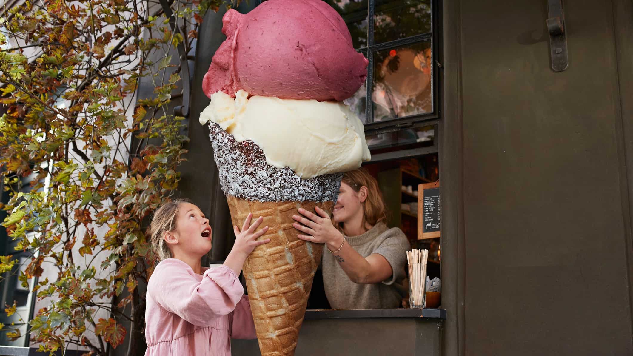 A girl is handed an oversized ice cream cone with lots of different flavours.