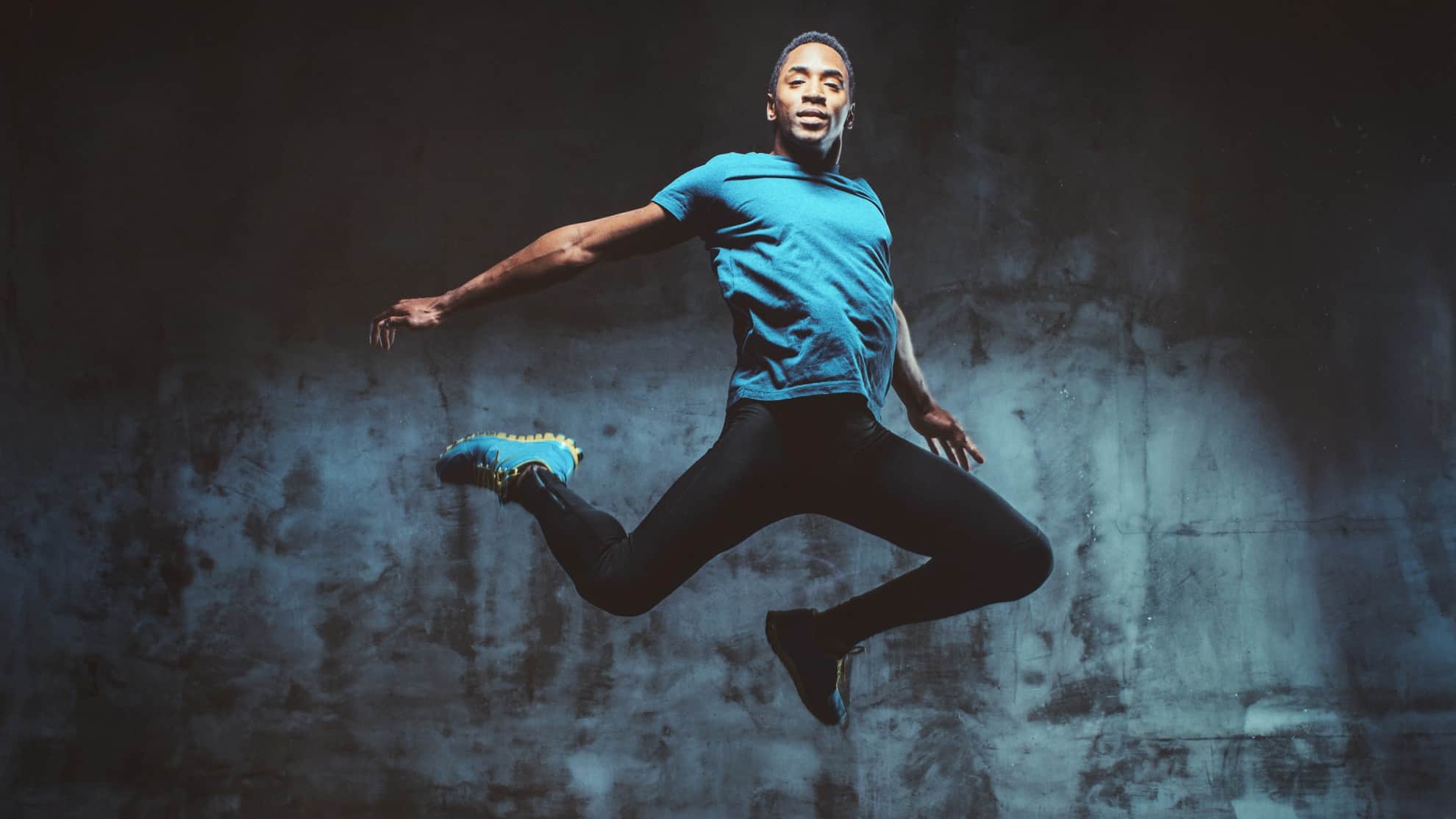 A male ballet dancer gracefully leaps high into the air during training.