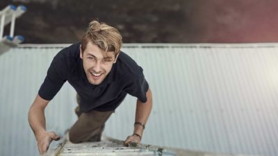 A young male worker climbs a ladder.