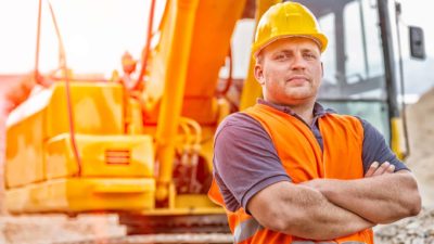Man with crossed arms wearing hard hat on mining or construction siter