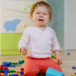 A little kid cries in frustration because her blocks fell over and broke.
