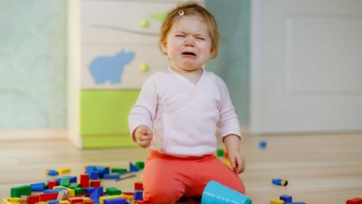 A little kid cries in frustration because her blocks fell over and broke.
