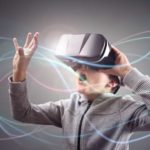 A boy wearing a virtual reality headset opens his arms in wonder