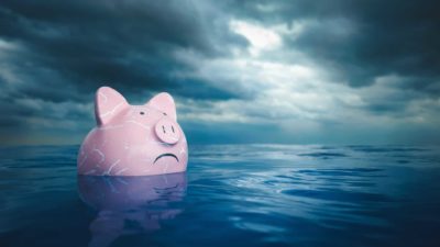 A worried pink piggy bank in dark waters, indicating pressure on the banking sector