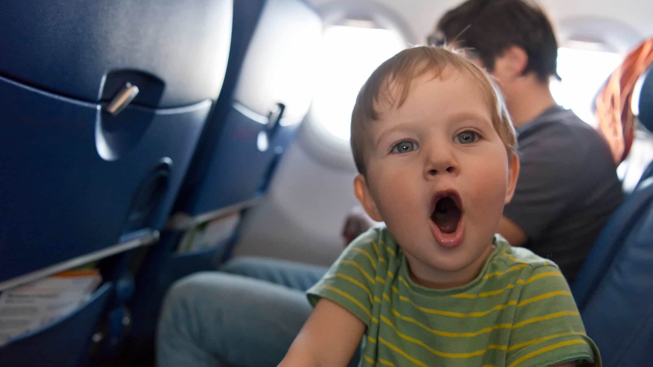 A little boy opens his mouth wide, excited about taking a plane trip.