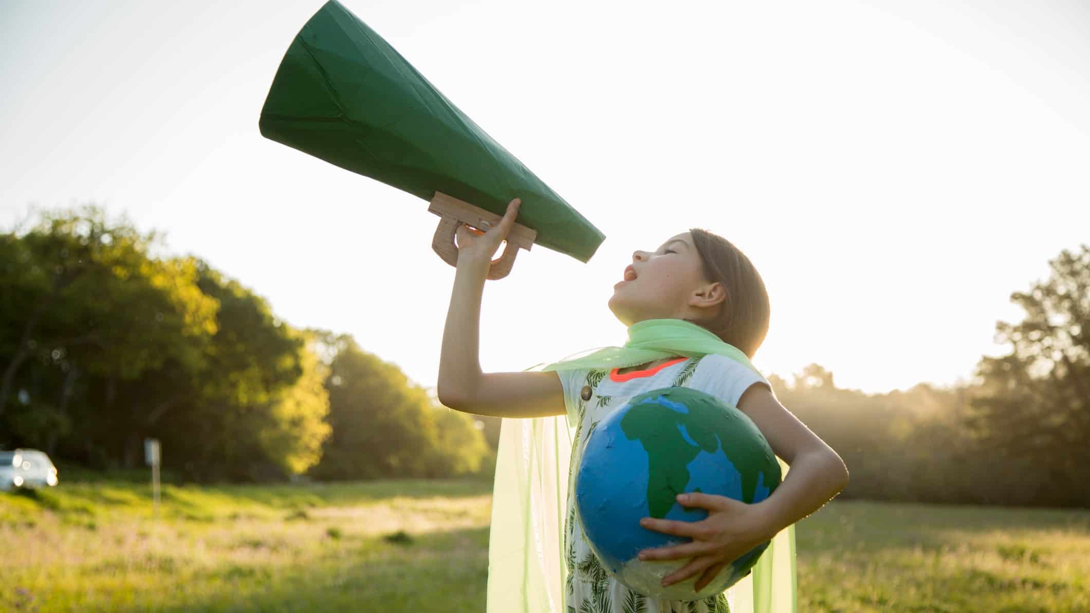 A girl holding a globe shouts into a green megaphone about climate change.