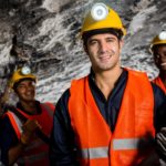 Three coal miners smiling while underground
