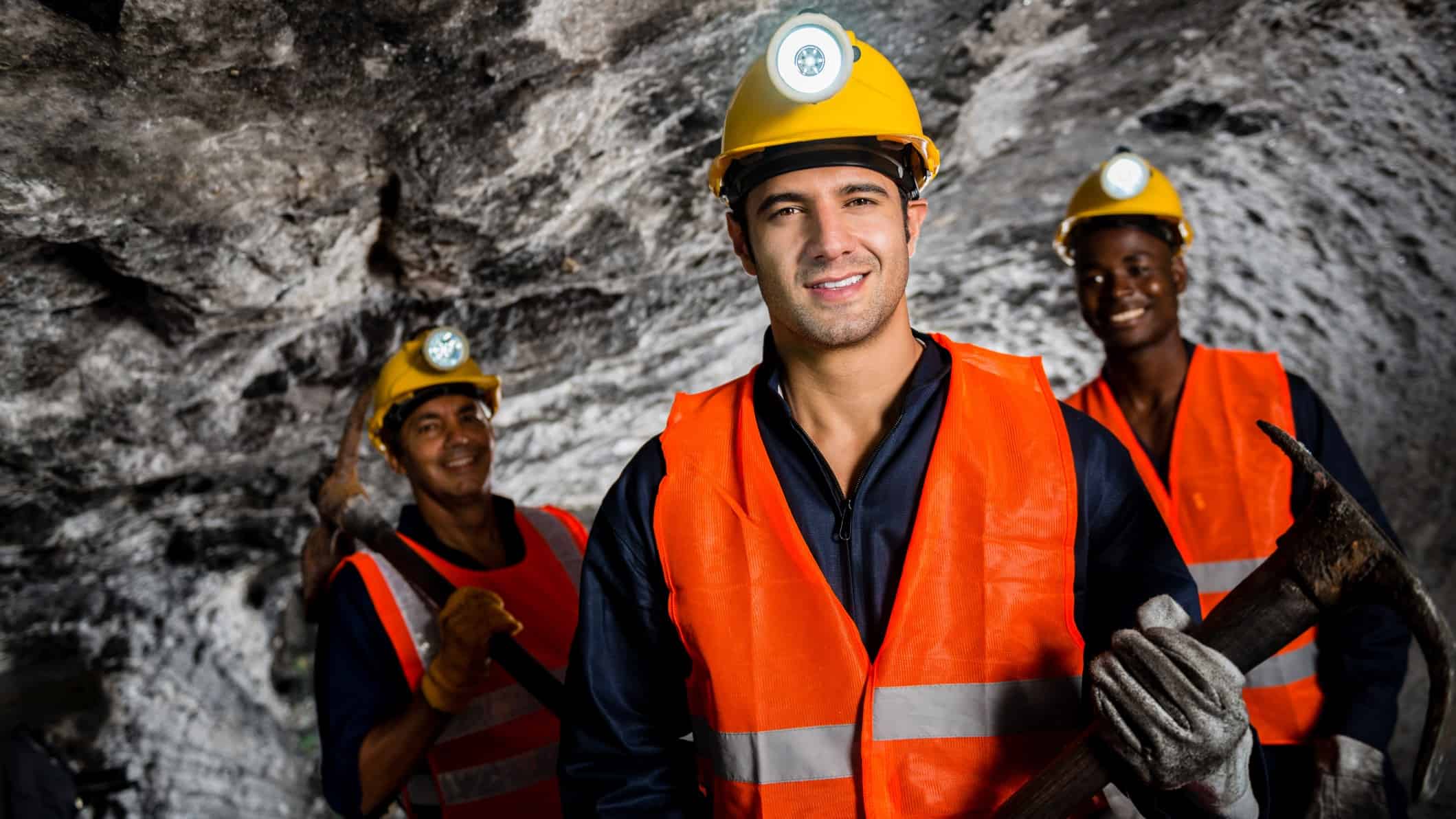Three coal miners smiling while underground