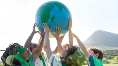 Group of children dressed in green hold up a globe relating to climate change.