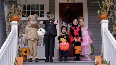 Kids in spooky costumes line up on a deck for Halloween