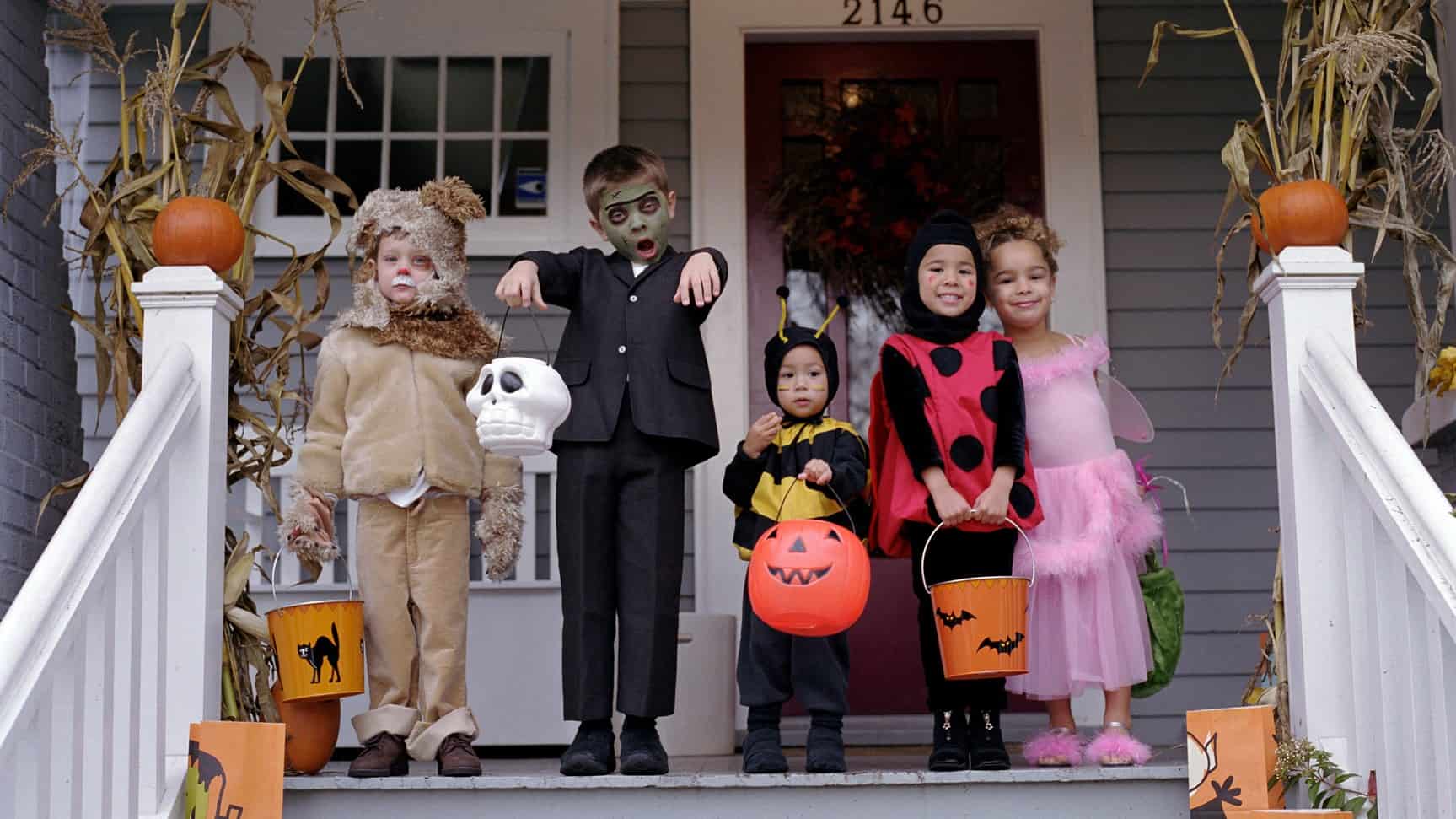Kids in spooky costumes line up on a deck for Halloween