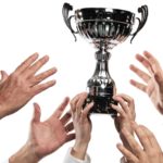 Rival hands reaching upward for a company trophy or prize.