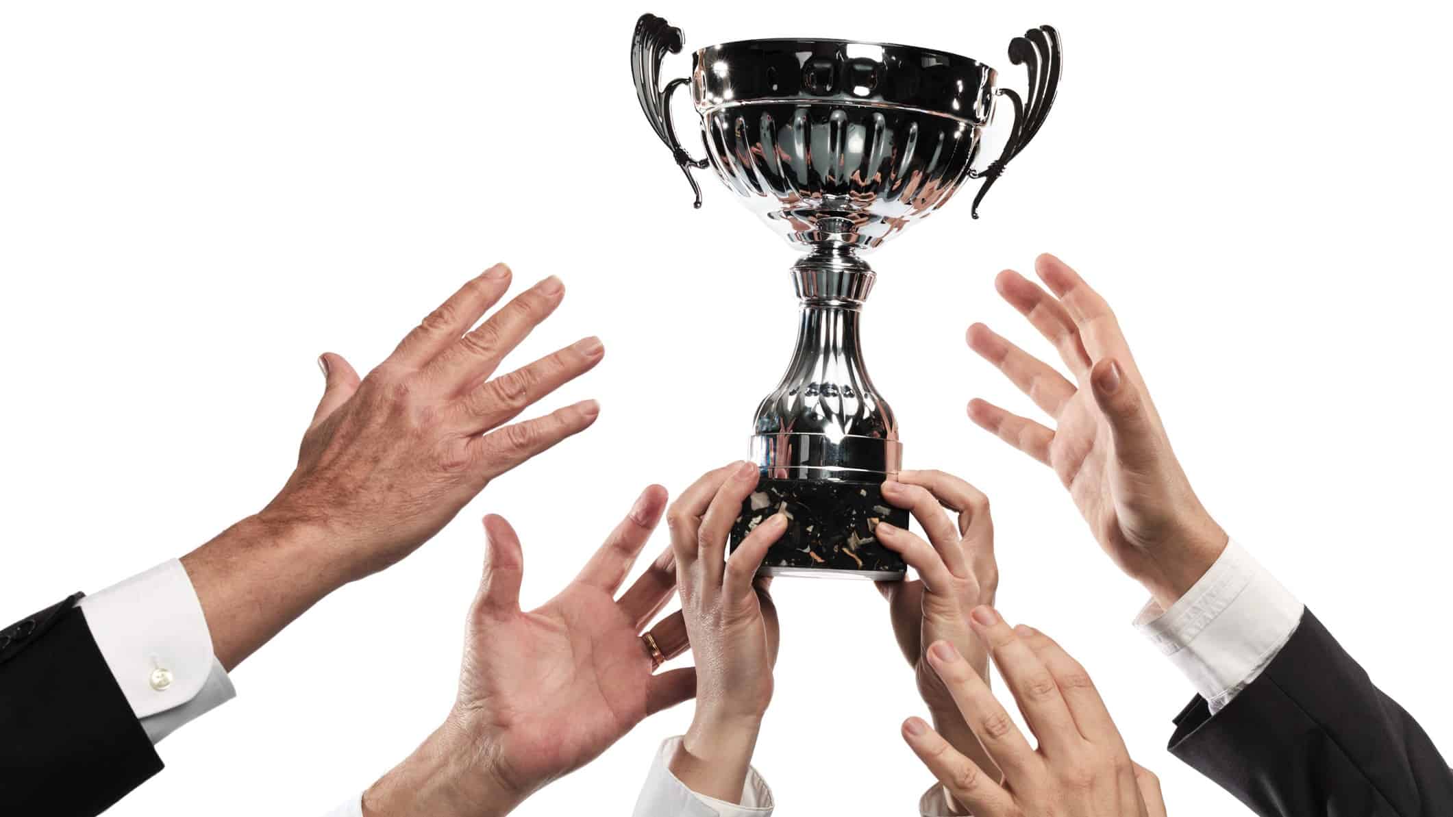 Rival hands reaching upward for a company trophy or prize.