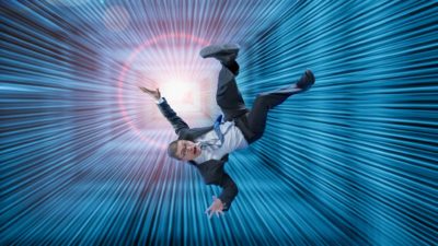 A man in a business suit plunges down a big square hole lit up in blue.
