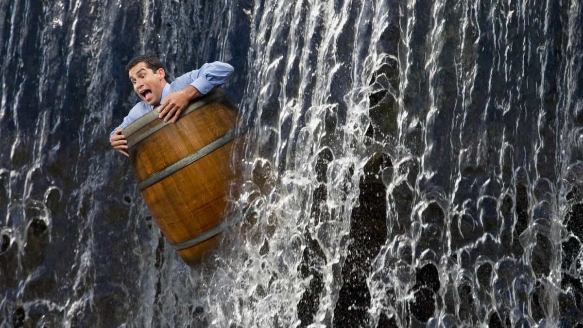 Businessman in a barrel plunges down a waterfall