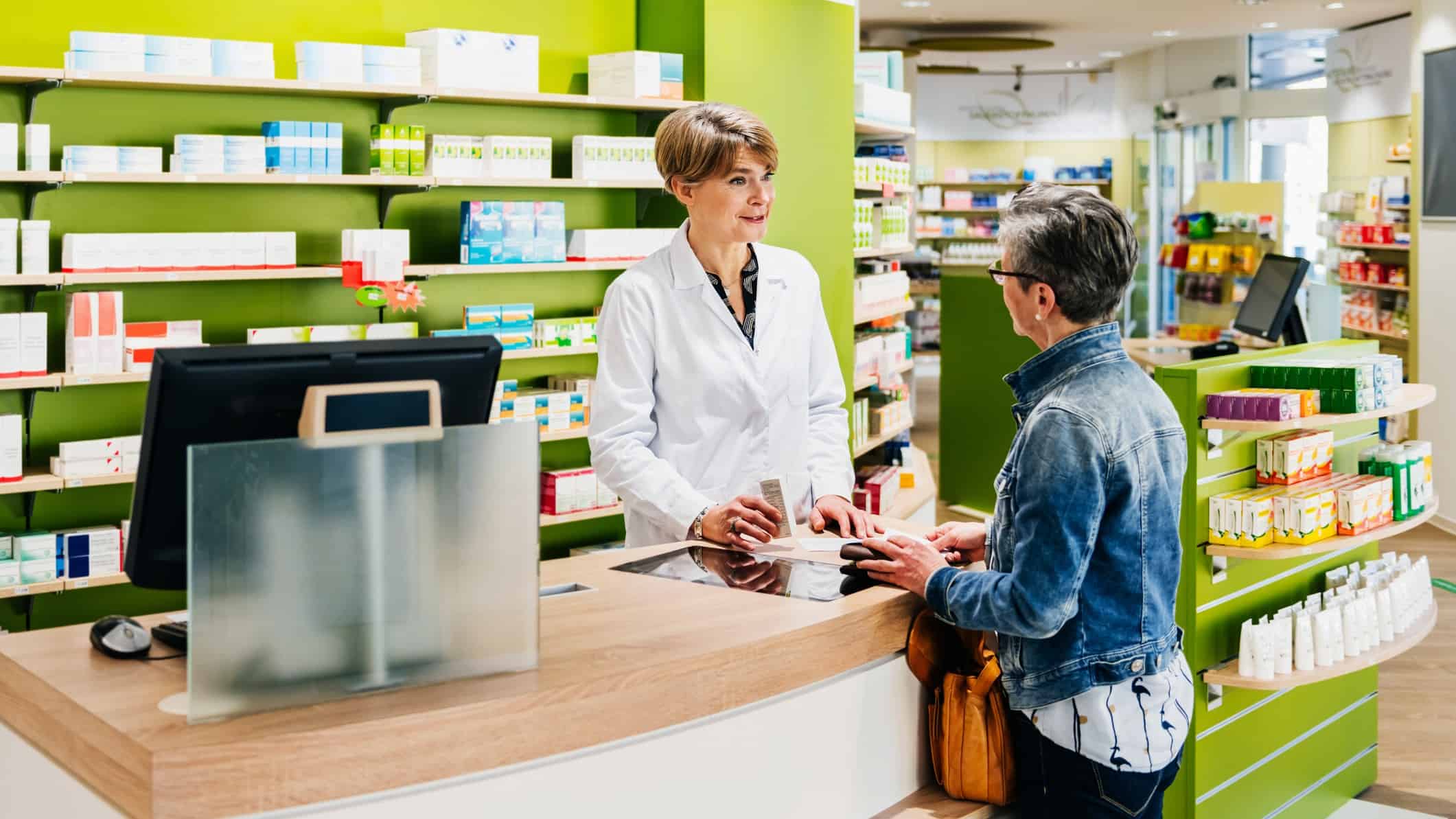 A senior pharmacist talks to a customer at the counter in a shop