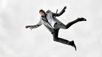 Man in suit plummets downwards in sky.