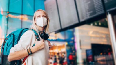 A woman wearing a mask at the airport gets ready to travel again with Qantas