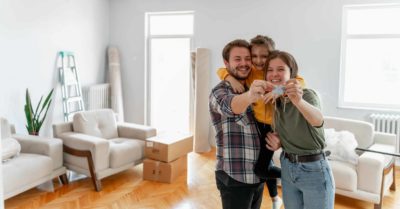 A couple and their child smiling happily in their new apartment holding their keys