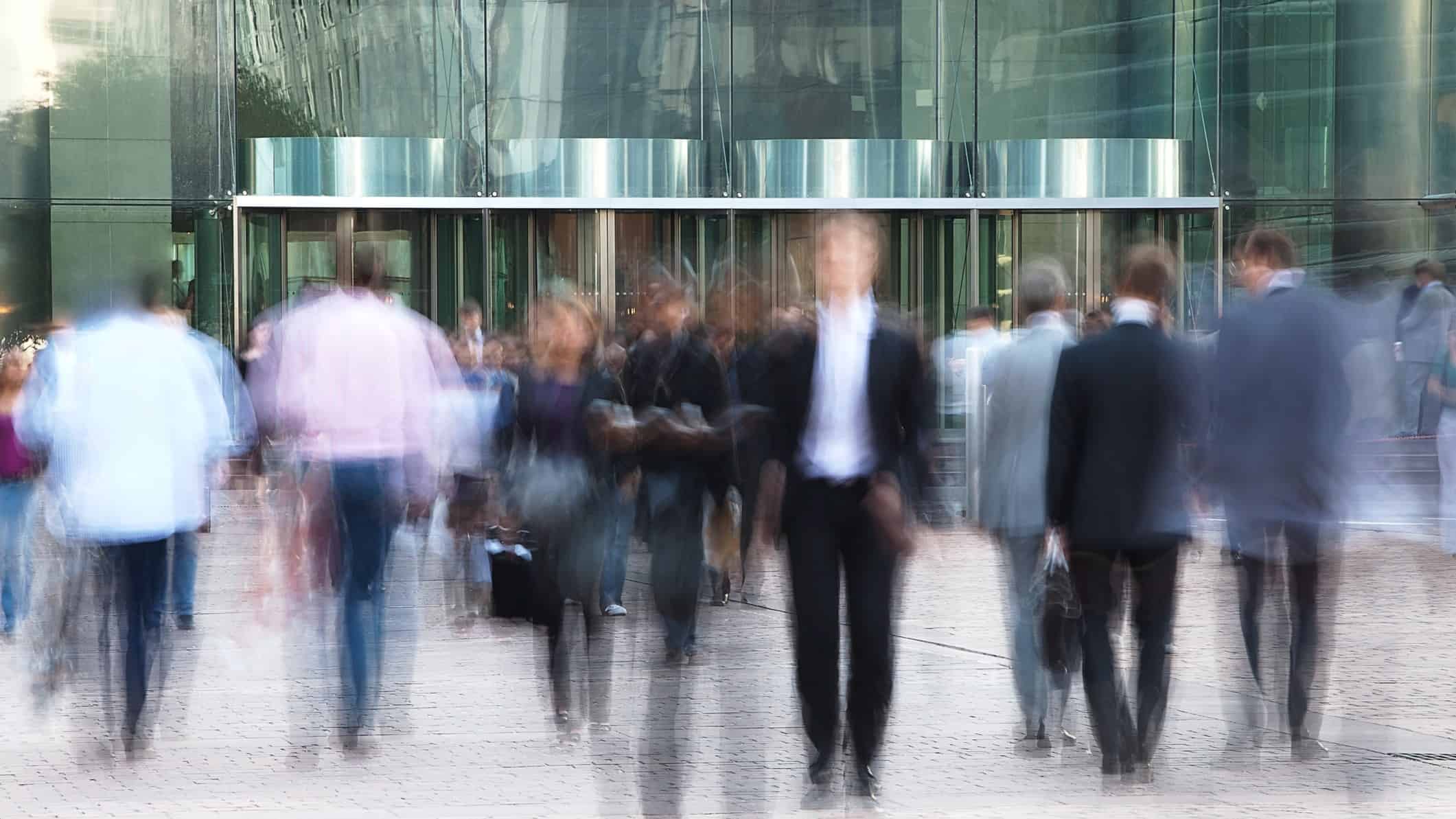 Concept image of blurry people outside an office with four revolving doors.