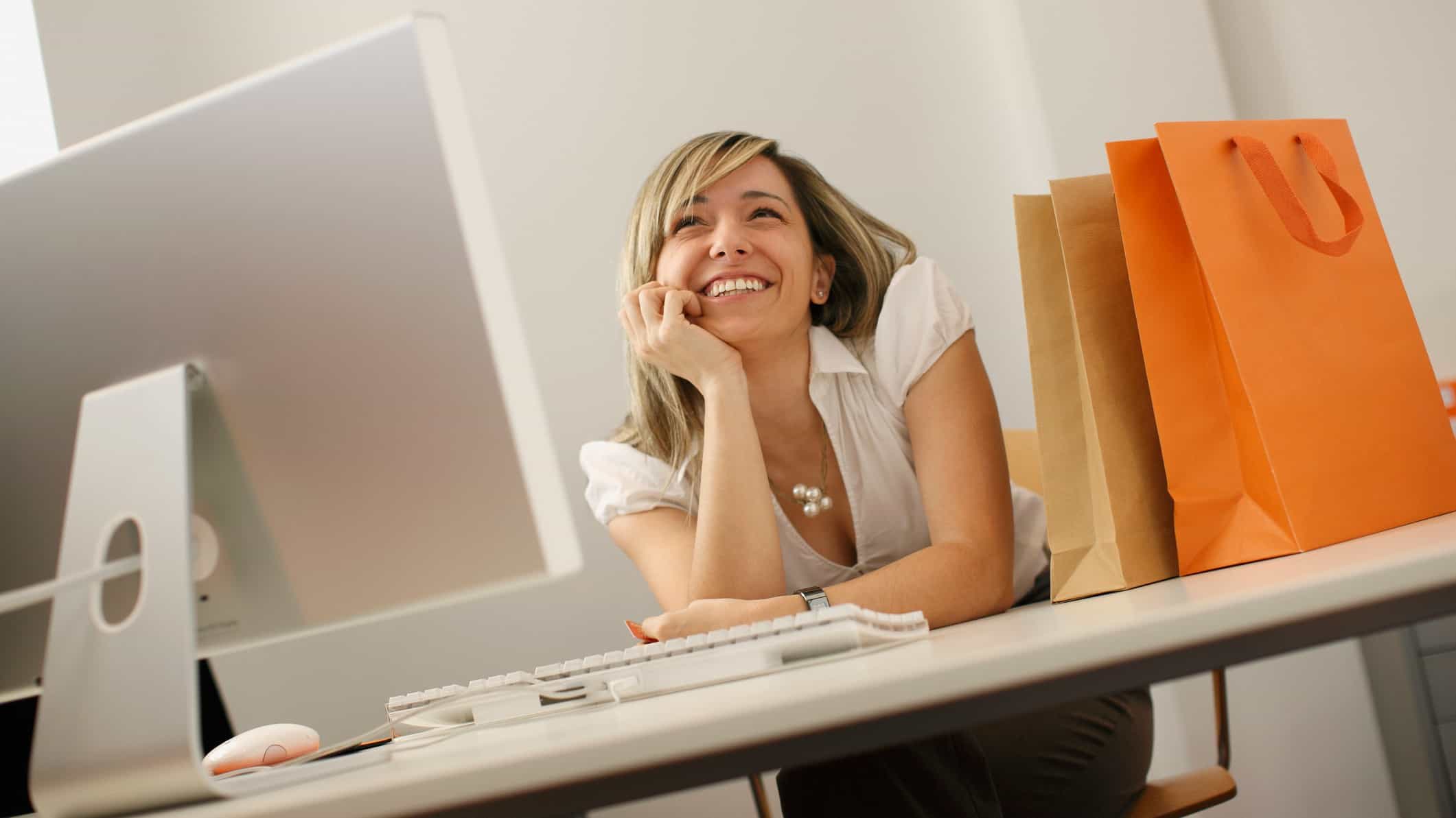 A smiling woman at her computer after a successful online shopping experience.