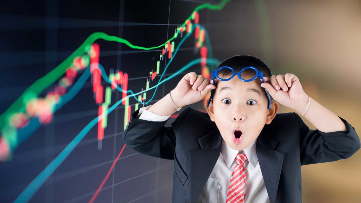 Young boy looks shocked as he lifts glasses above his eyes in front of a stock market graph. representing three ASX 300 shares hitting 52-week lows today
