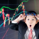 Young boy looks shocked as he lifts glasses above his eyes in front of a stock market graph. representing three ASX 300 shares hitting 52-week lows today