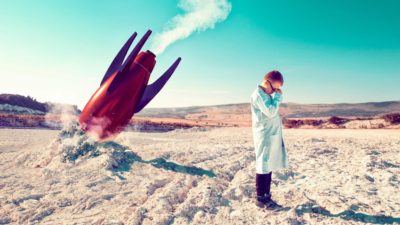 Codan share price A dismayed kid dressed as a scientist stands with his back to a rocket crashed into the ground