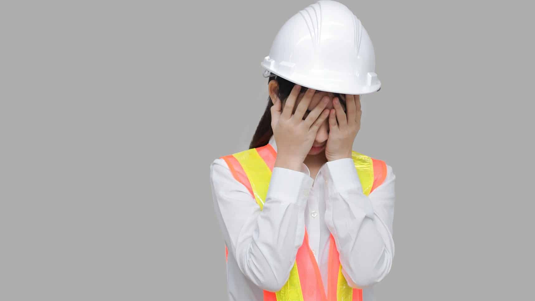 ASX 200 mining shares downgrade Female worker with hard hat puts head in hands