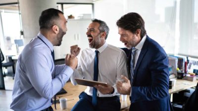 A group of men in the office celebrate after winning big.