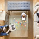 A family sits around the living room, each on a different device.