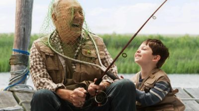 A young boy laughs with his grandpa as he puts a fishing net over his head.