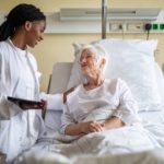 A patient in a hospital bed is reassured by a doctor.
