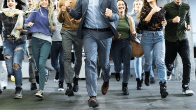 a group of people run towards the camera wearing business and smart casual clothes.