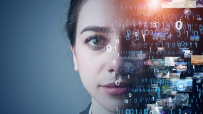 a woman stares ahead with a serious expression on her face while half of her face is covered by computer coding, indicative of artificial intelligence and machine learning technology.