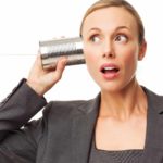 a woman in a business suit looks wide eyed and interested as she holds a tin can with string to hear ear listening to some news.