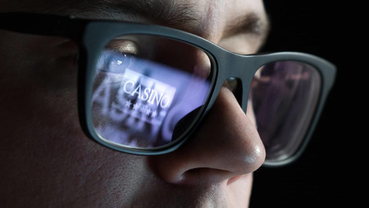 a close up of a man wearing dark glasses with the word "casino" and stars reflected in the glass of one of his eyes.