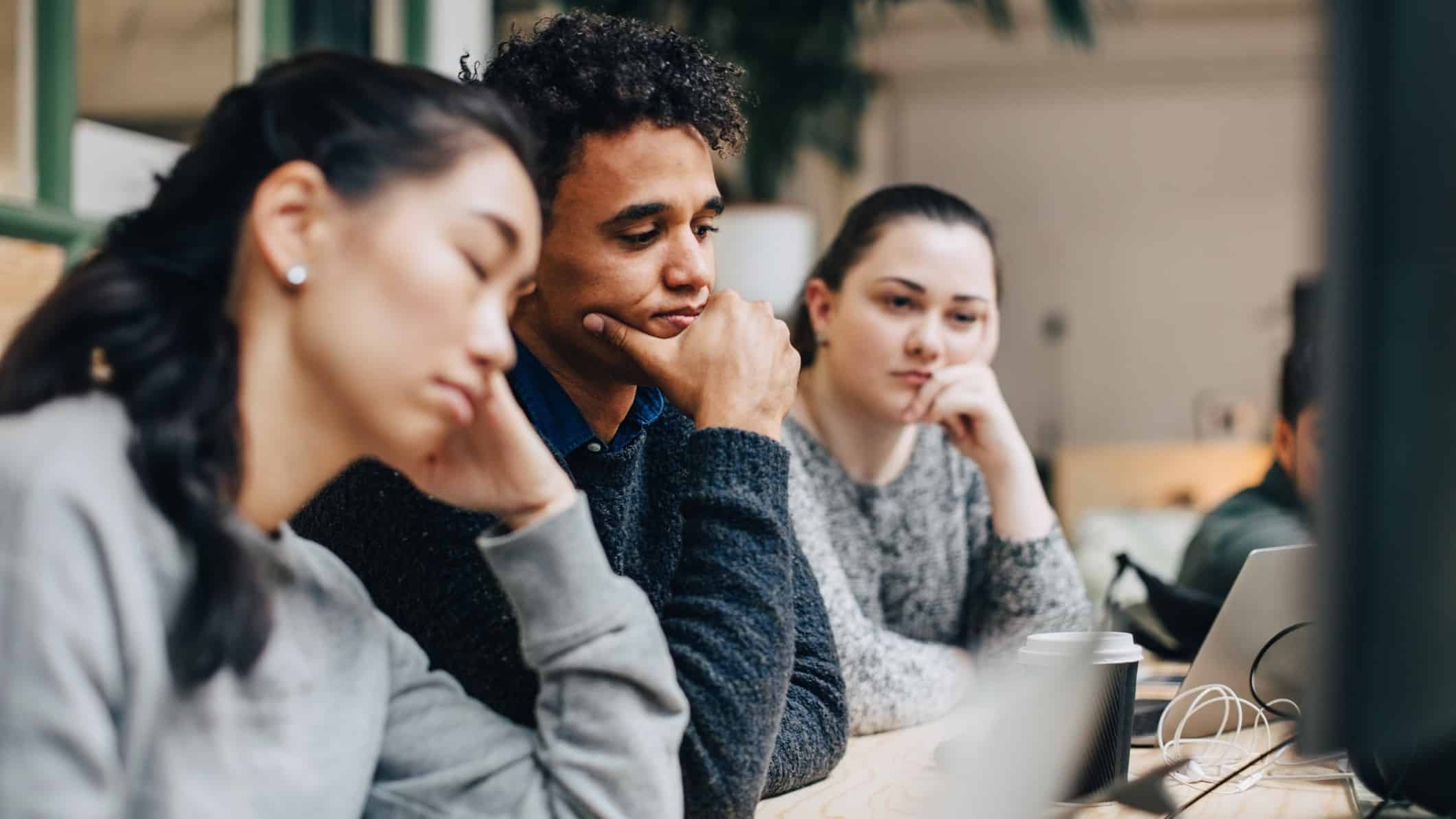 Three workers are not pleased, seeing the lousy news on a computer.