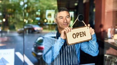 A man turns the open sign on his shop window.