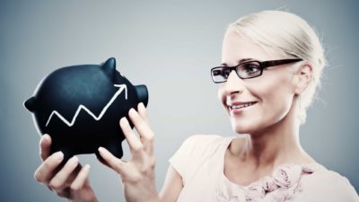 Rising arrow on a piggy bank with a woman holding it and smiling.