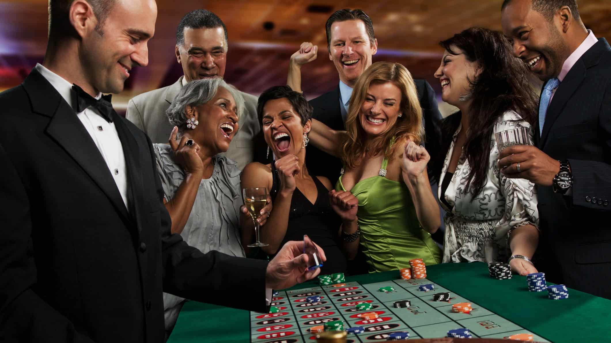 group of people cheer at blackjack table at casino.