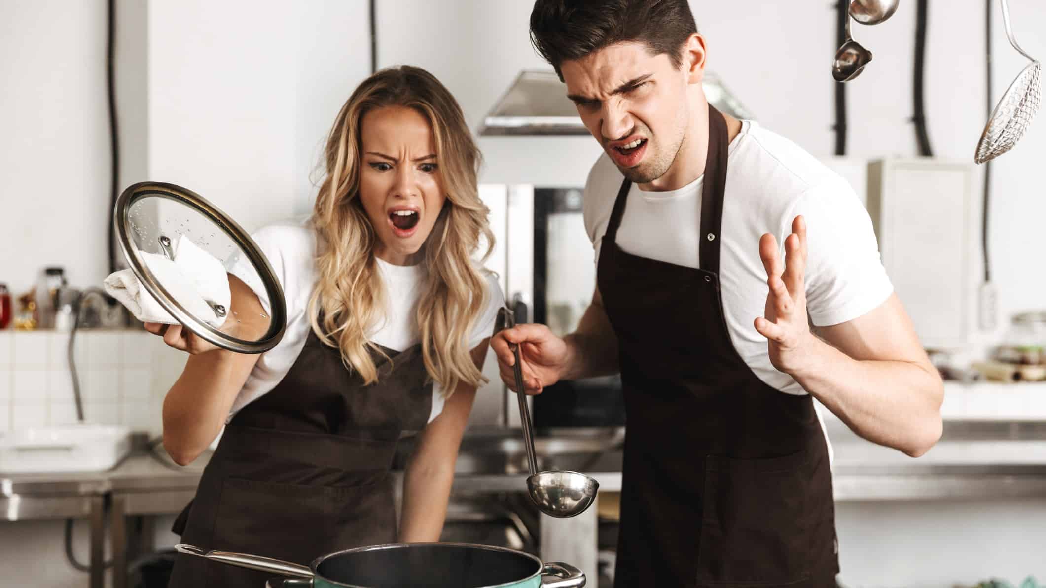 Displeased shocked emotional young friends loving couple chefs on the kitchen cooking.