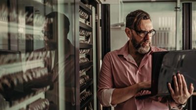 Tesserent cybersecurity professional man inspects server room and works on laptop