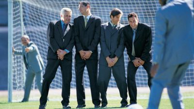 Men standing together and defending the goal post symbolising defensive shares.