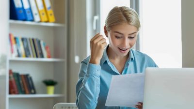 Young investor sits at desk looking happy after discovering Westpac's dividend reinvestment plan